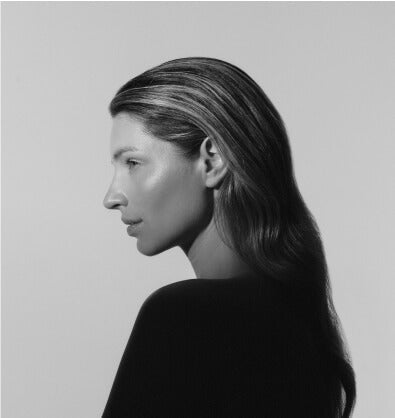 Black and white profile portrait of a woman with long hair wearing a dark top against a plain background