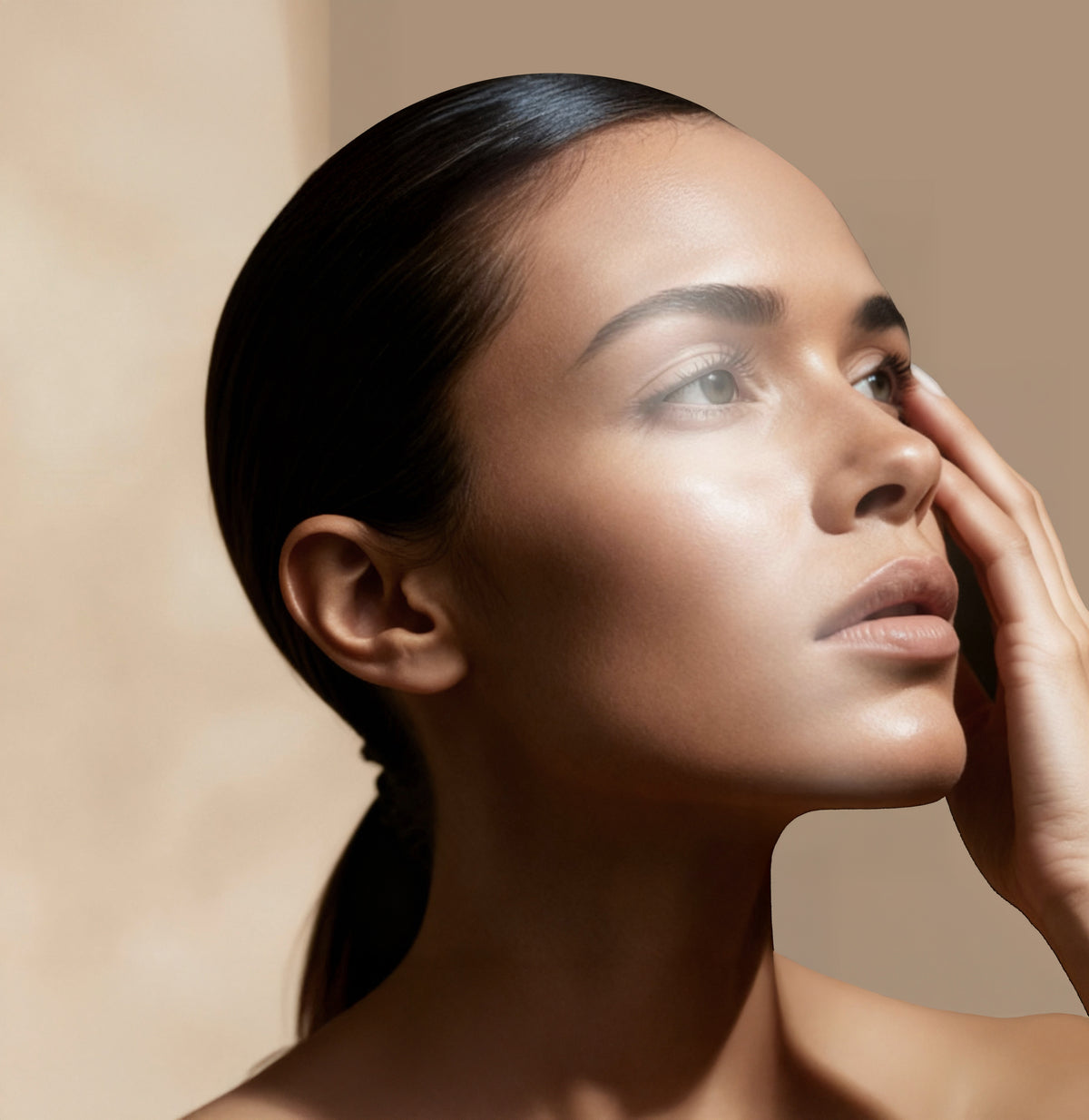 Close-up of a woman with smooth skin touching her face against a warm beige background