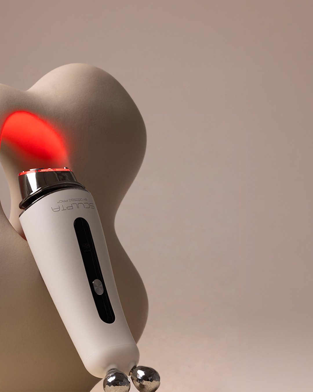 Sculpta by Déesse PRO with a red LED glow against a sculptural form